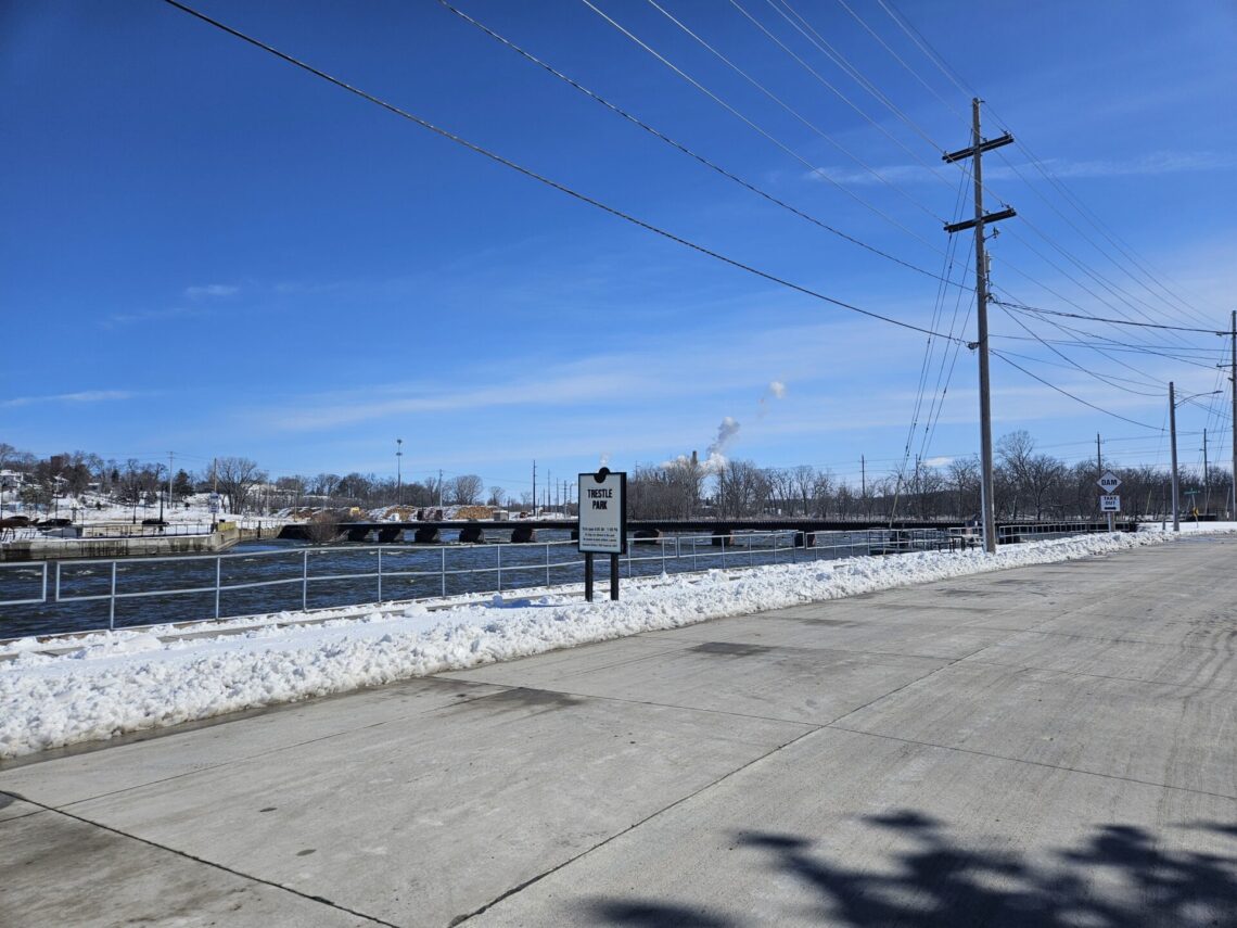 Picture of Trestle Park sign in winter with a bridge in the background