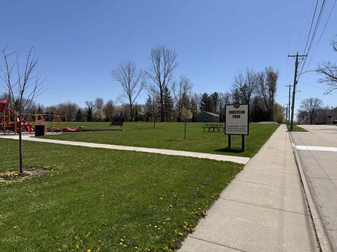 Sign for Anderson Park with sidewalk leading to playground equipment