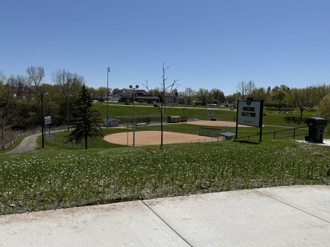 Picture of a sign that says Horseshoe Valley Park with two baseball diamonds in the background.