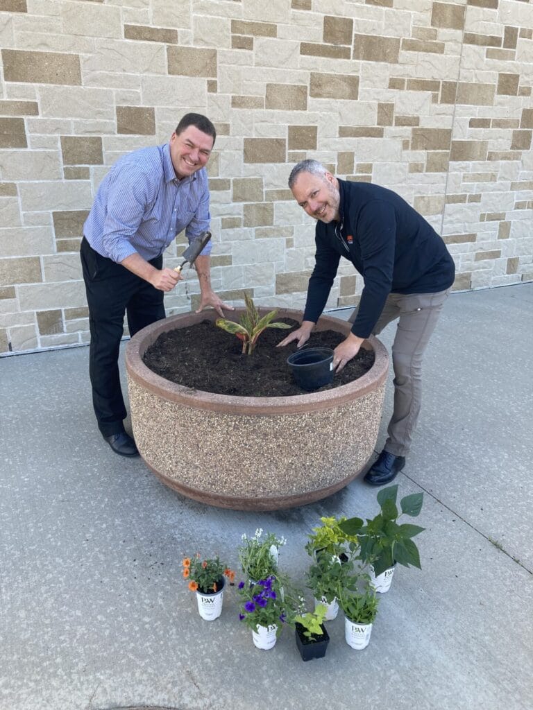 Police Chief Jamie Graff and Assistant Police Chief Bradley Sanderfoot plant flowers in pots outside Police Department as part of annual beautification project.