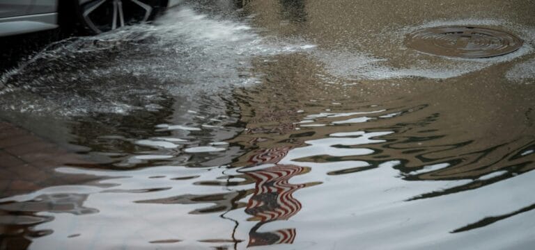 Stock image of a car tire driving through a puddle by Connor McManus.