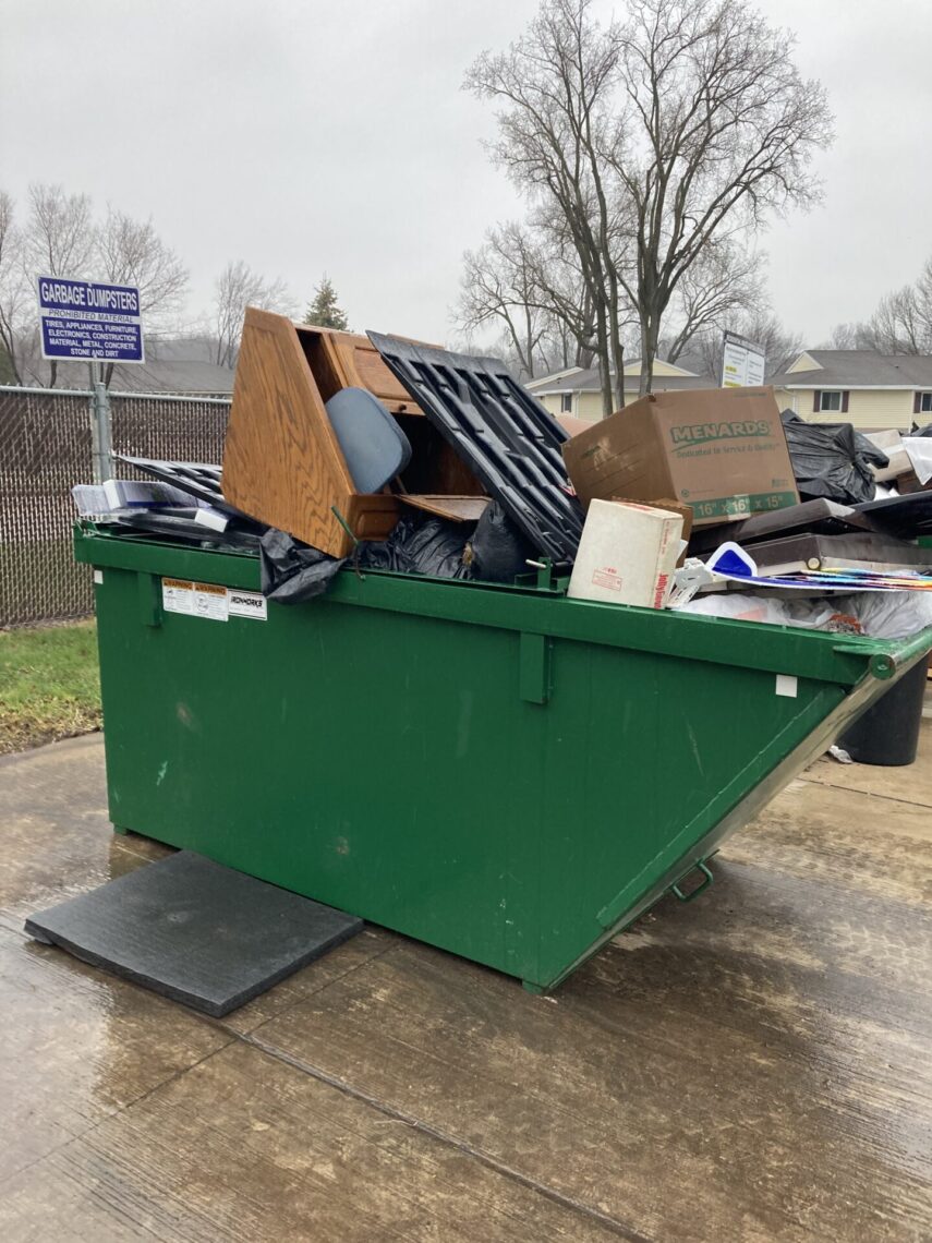 Picture of a green dumpster overflowing with furniture