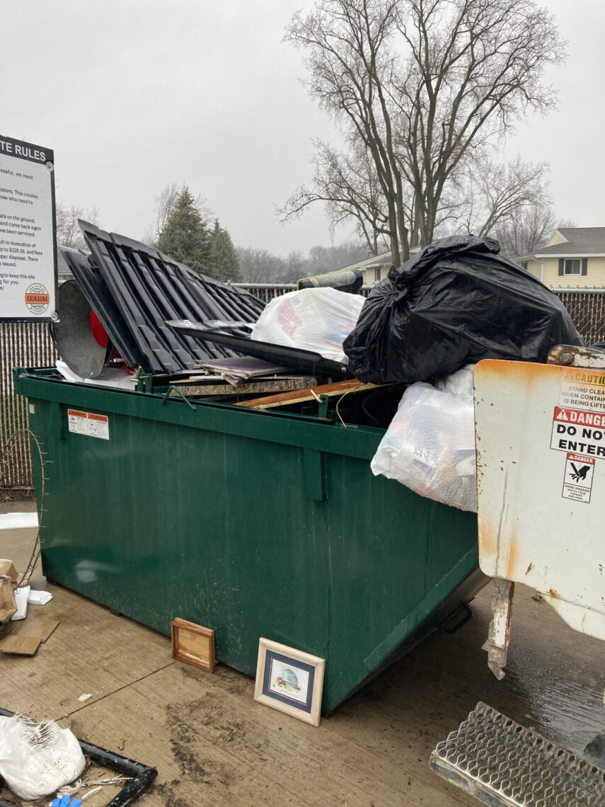 Picture of a dumpster overflowing with full garbage bags
