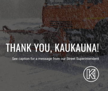 A snowplow clearing a snow-covered road in Kaukauna, with snow falling heavily. Bold text over the image reads, 