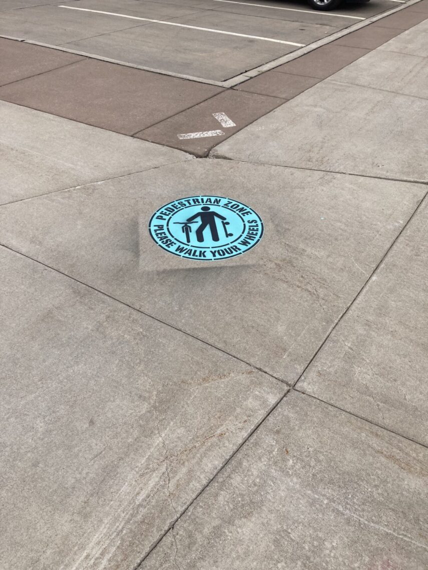 Sidewalk with a circular blue painted area that reads 